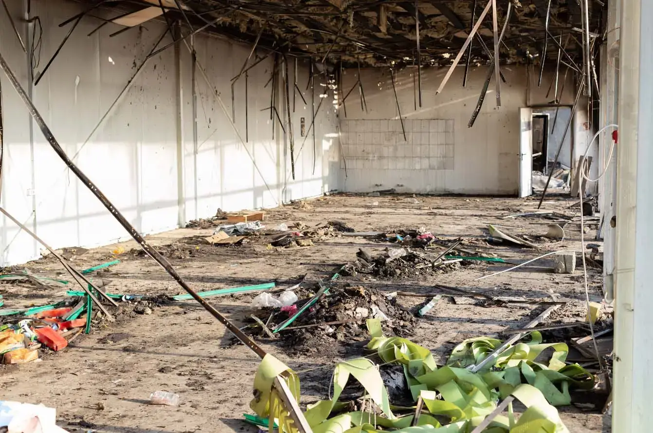Charred debris and exposed metal hang from the ceiling of a fire-damaged building, highlighting structural resilience and the need for fireproofing